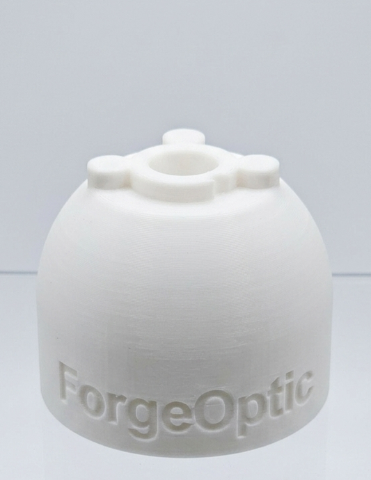 A white 3D-printed dome-shaped capsulorhexis simulator with the brand name 'ForgeOptic' embossed on the front, displayed on a clear acrylic stand against a light gray background.